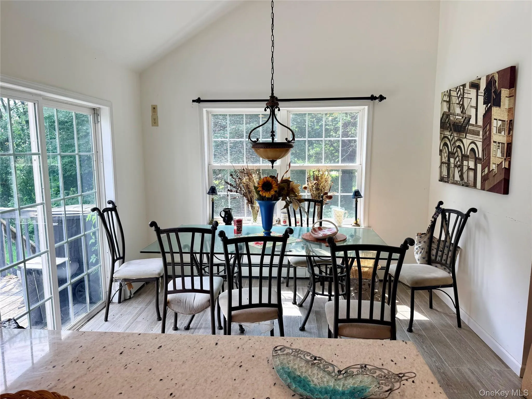 Vaulted ceiling, sliding glass door, pendant light fixture, and window with outdoor scenery. Vaulted ceiling, sliding glass door, pendant light fixture, and window with outdoor scenery.