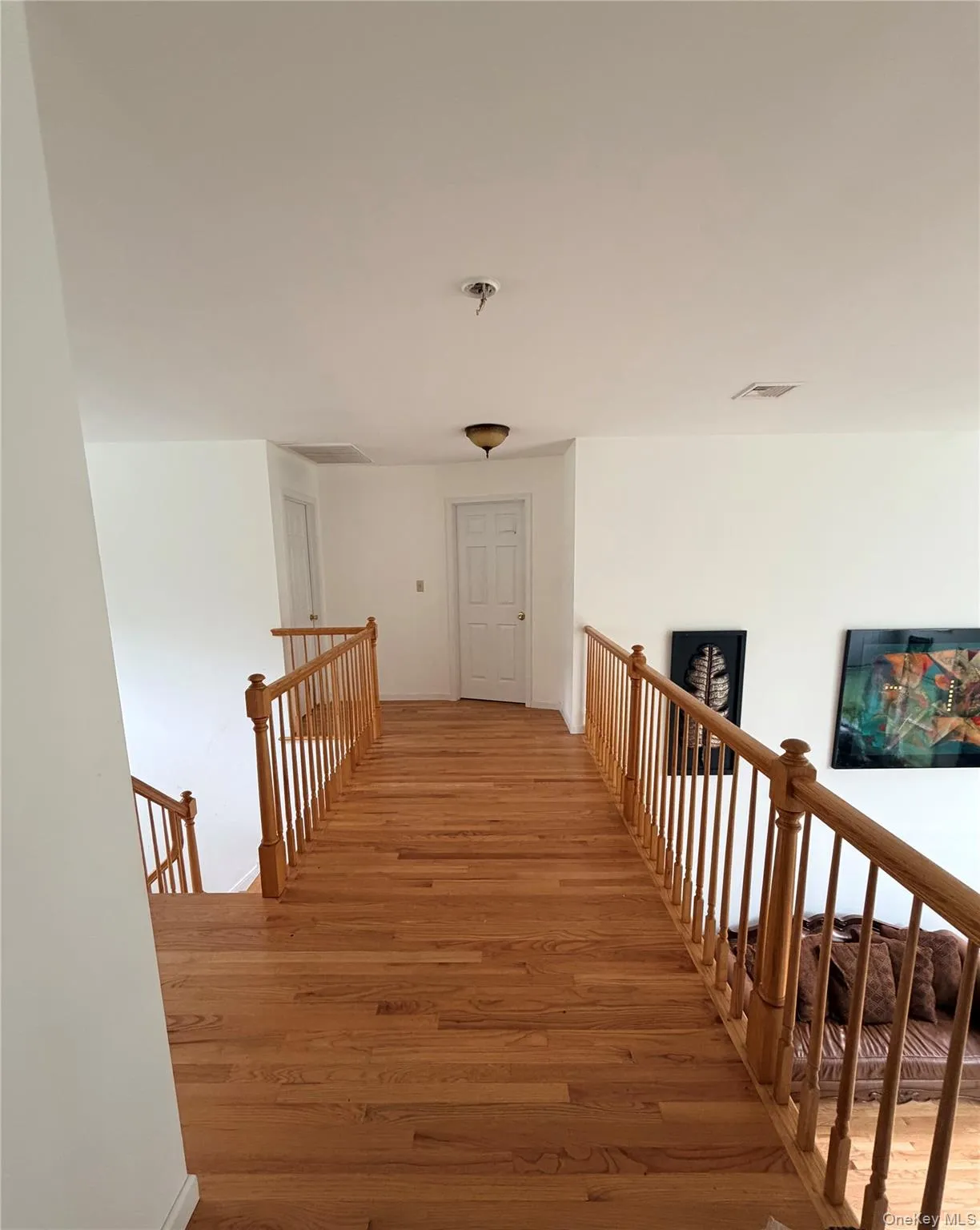 Hardwood flooring throughout, with natural wood balusters and newel posts, white interior doors, and a ceiling-mounted light fixture Hardwood flooring throughout, with natural wood balusters and newel posts, white interior doors, and a ceiling-mounted light fixture
