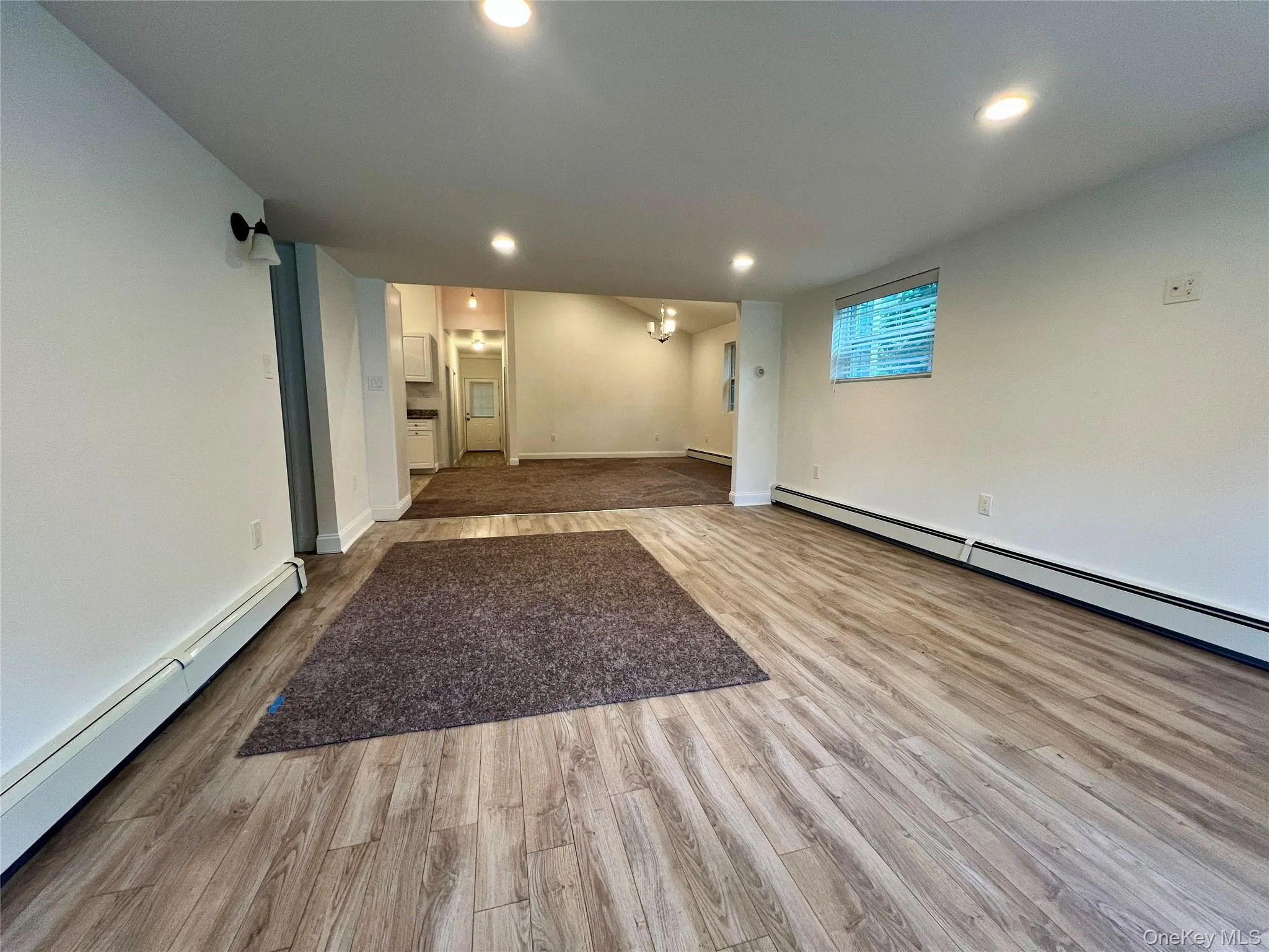 Empty room with a baseboard heating unit, wood finished floors, and recessed lighting Empty room with a baseboard heating unit, wood finished floors, and recessed lighting