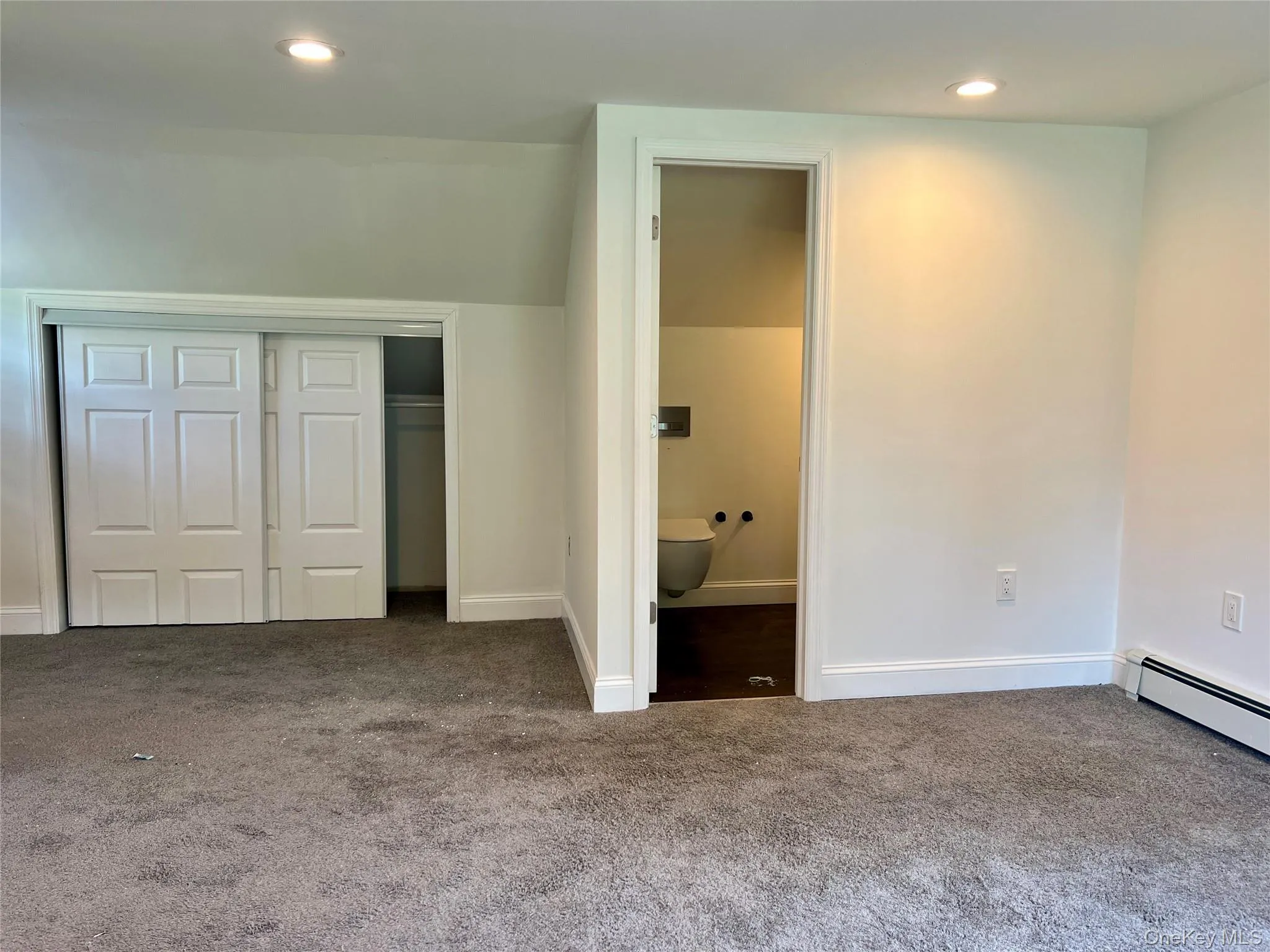 Unfurnished bedroom featuring carpet floors, a closet, baseboard heating, recessed lighting, and ensuite bath Unfurnished bedroom featuring carpet floors, a closet, baseboard heating, recessed lighting, and ensuite bath