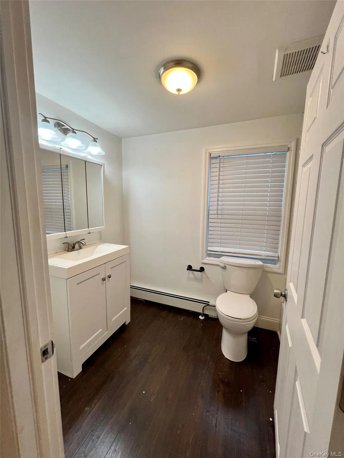 Half bathroom featuring baseboard heating, hardwood / wood-style flooring, and vanity Half bathroom featuring baseboard heating, hardwood / wood-style flooring, and vanity
