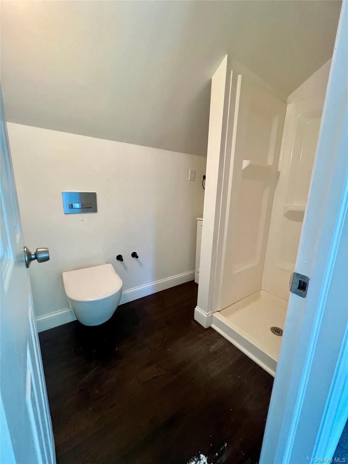 Bathroom with a stall shower, wood finished floors, and lofted ceiling Bathroom with a stall shower, wood finished floors, and lofted ceiling