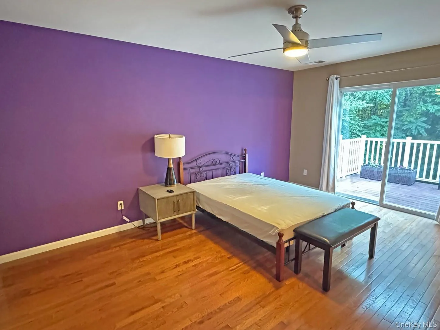 Hardwood flooring, ceiling fan with integrated lighting, sliding glass door, and exterior deck with white railing Hardwood flooring, ceiling fan with integrated lighting, sliding glass door, and exterior deck with white railing