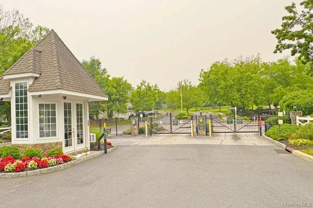 Gated entry with a guardhouse featuring a shingled roof and stone base Gated entry with a guardhouse featuring a shingled roof and stone base