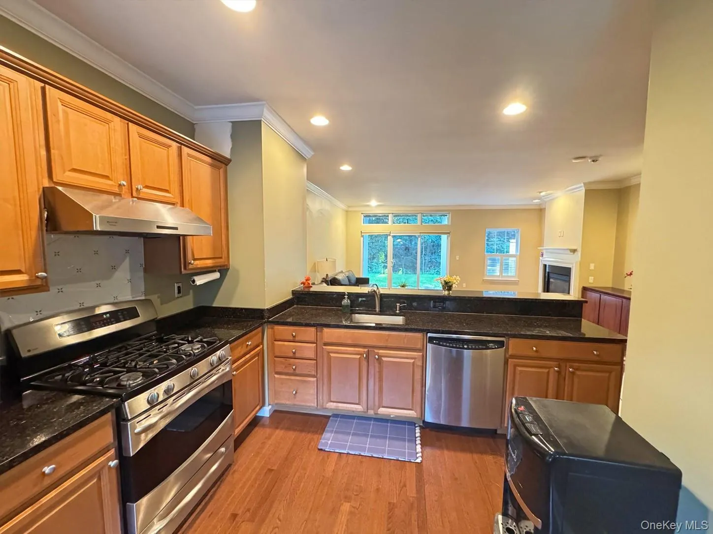 Kitchen featuring wood-finish cabinetry, dark stone countertops, stainless steel appliances, and wood-finish flooring Kitchen featuring wood-finish cabinetry, dark stone countertops, stainless steel appliances, and wood-finish flooring
