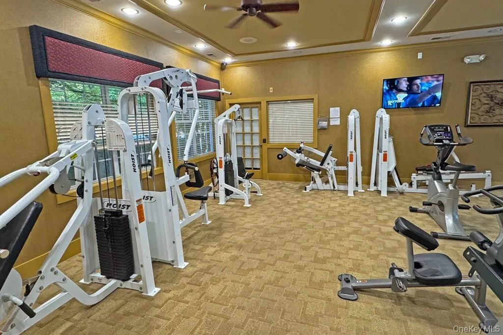 Fitness area featuring recessed lighting, a ceiling fan, patterned carpet flooring, and a wall-mounted television Fitness area featuring recessed lighting, a ceiling fan, patterned carpet flooring, and a wall-mounted television