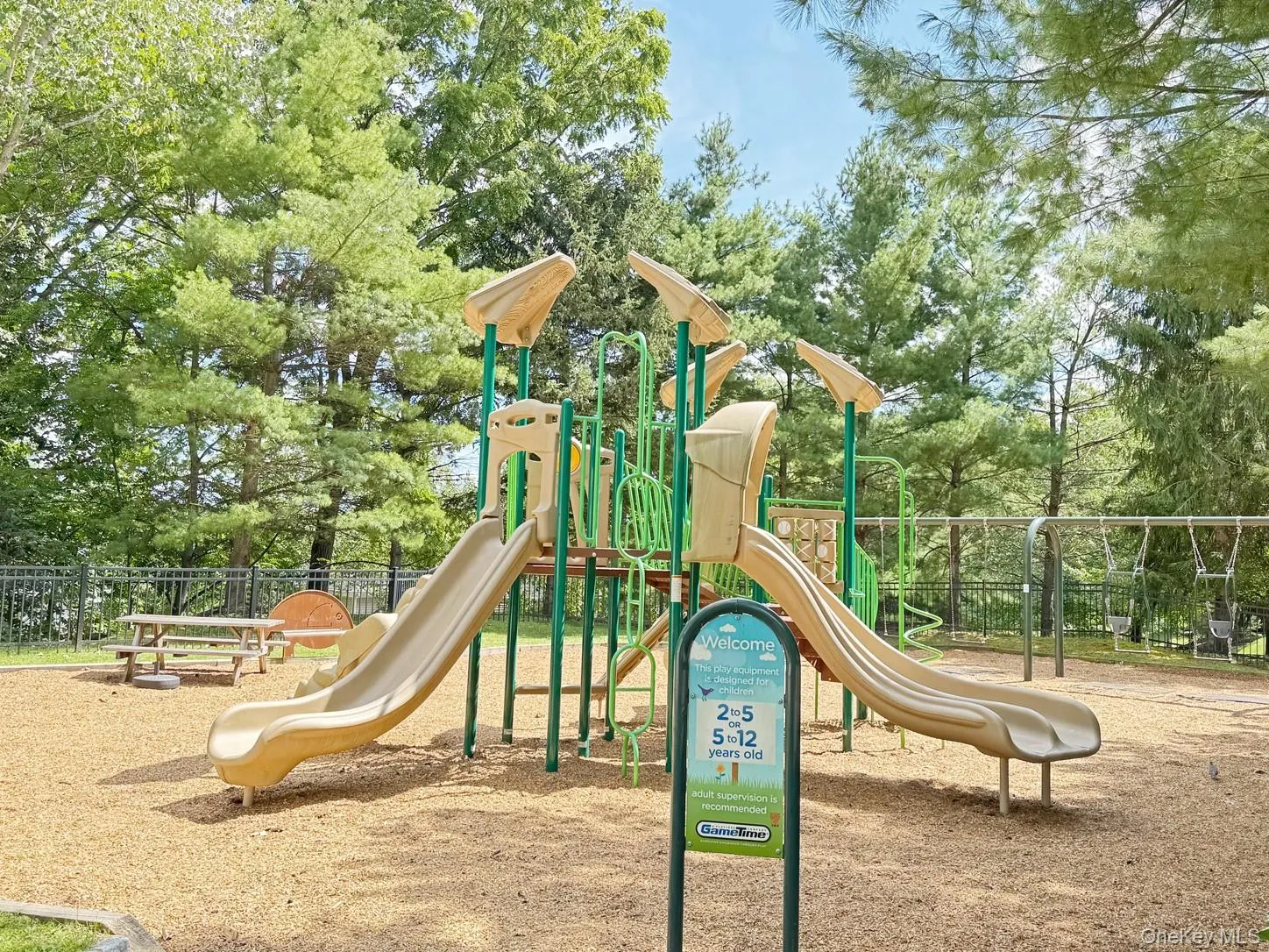 Playground featuring multiple slides, swing sets, and wood chip surfacing Playground featuring multiple slides, swing sets, and wood chip surfacing