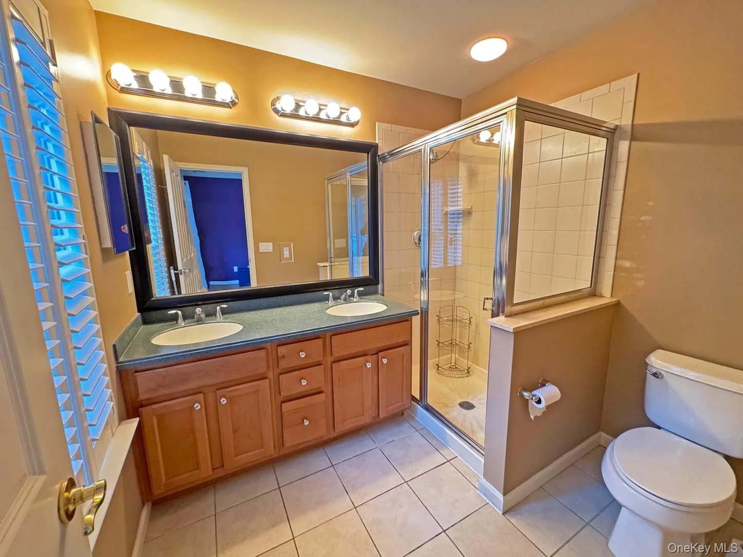 Dual vanity with undermount sinks, wood-finish cabinetry, and a large wall-mounted mirror Dual vanity with undermount sinks, wood-finish cabinetry, and a large wall-mounted mirror