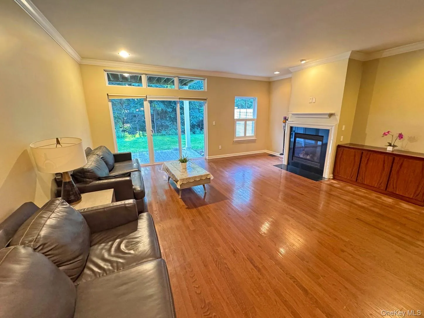 Hardwood flooring, crown molding, fireplace with mantel, built-in cabinetry, and sliding glass door Hardwood flooring, crown molding, fireplace with mantel, built-in cabinetry, and sliding glass door