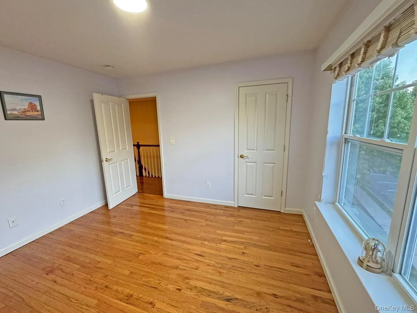 Hardwood flooring, white paneled doors, and natural light from the large window Hardwood flooring, white paneled doors, and natural light from the large window