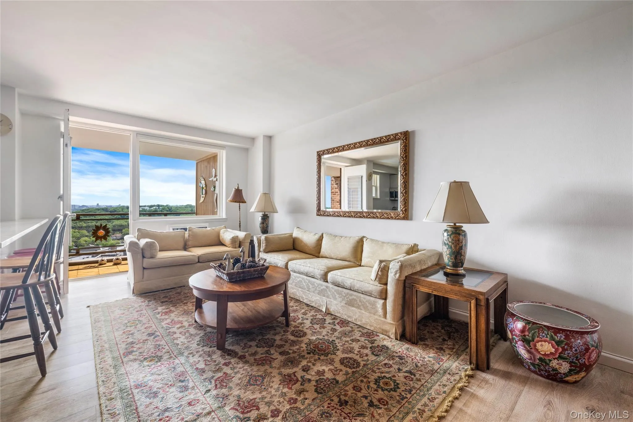 Expansive living area with light-colored wood-finish flooring, white walls, and a large balcony access Expansive living area with light-colored wood-finish flooring, white walls, and a large balcony access