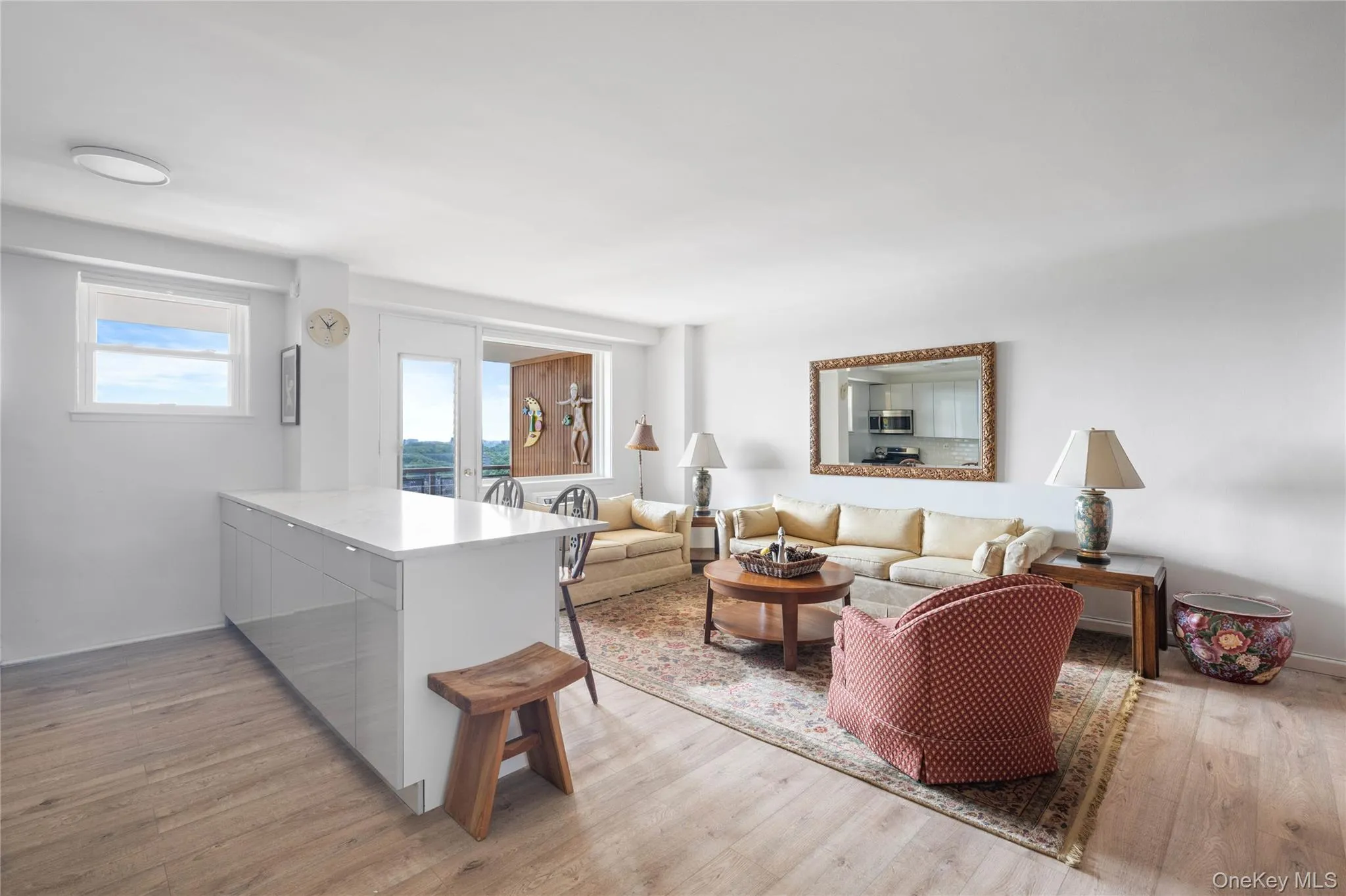 Light wood-finish flooring, white walls, and a contemporary kitchen island with a light-toned countertop Light wood-finish flooring, white walls, and a contemporary kitchen island with a light-toned countertop