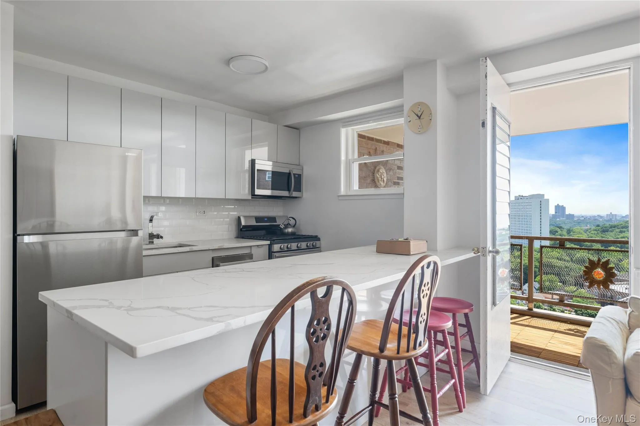Kitchen featuring white shaker cabinetry, stainless steel appliances, and a breakfast bar with a stone-finish countertop Kitchen featuring white shaker cabinetry, stainless steel appliances, and a breakfast bar with a stone-finish countertop
