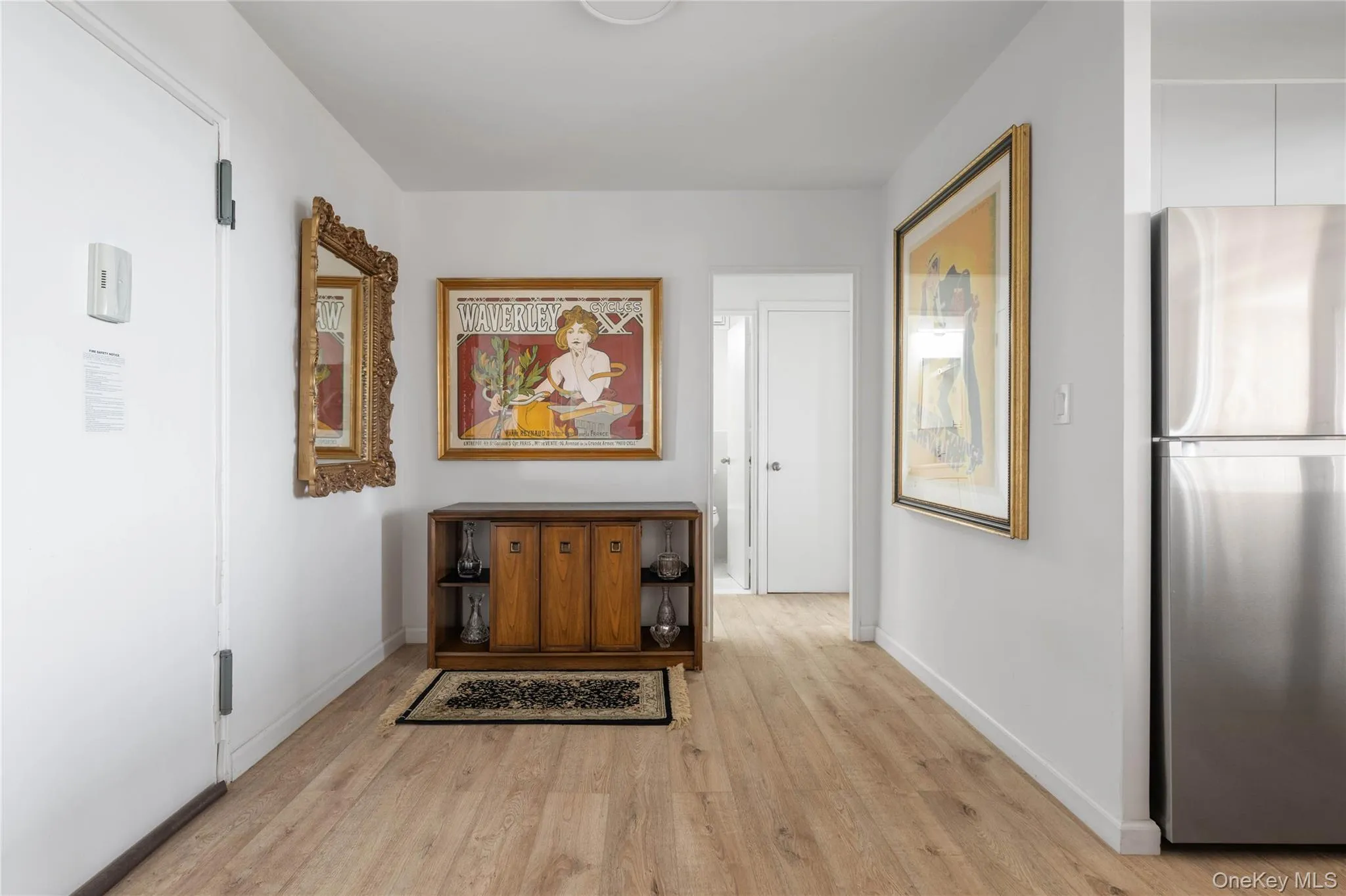 Wood-finish flooring throughout, bright white walls, stainless steel refrigerator, and recessed ceiling lighting Wood-finish flooring throughout, bright white walls, stainless steel refrigerator, and recessed ceiling lighting