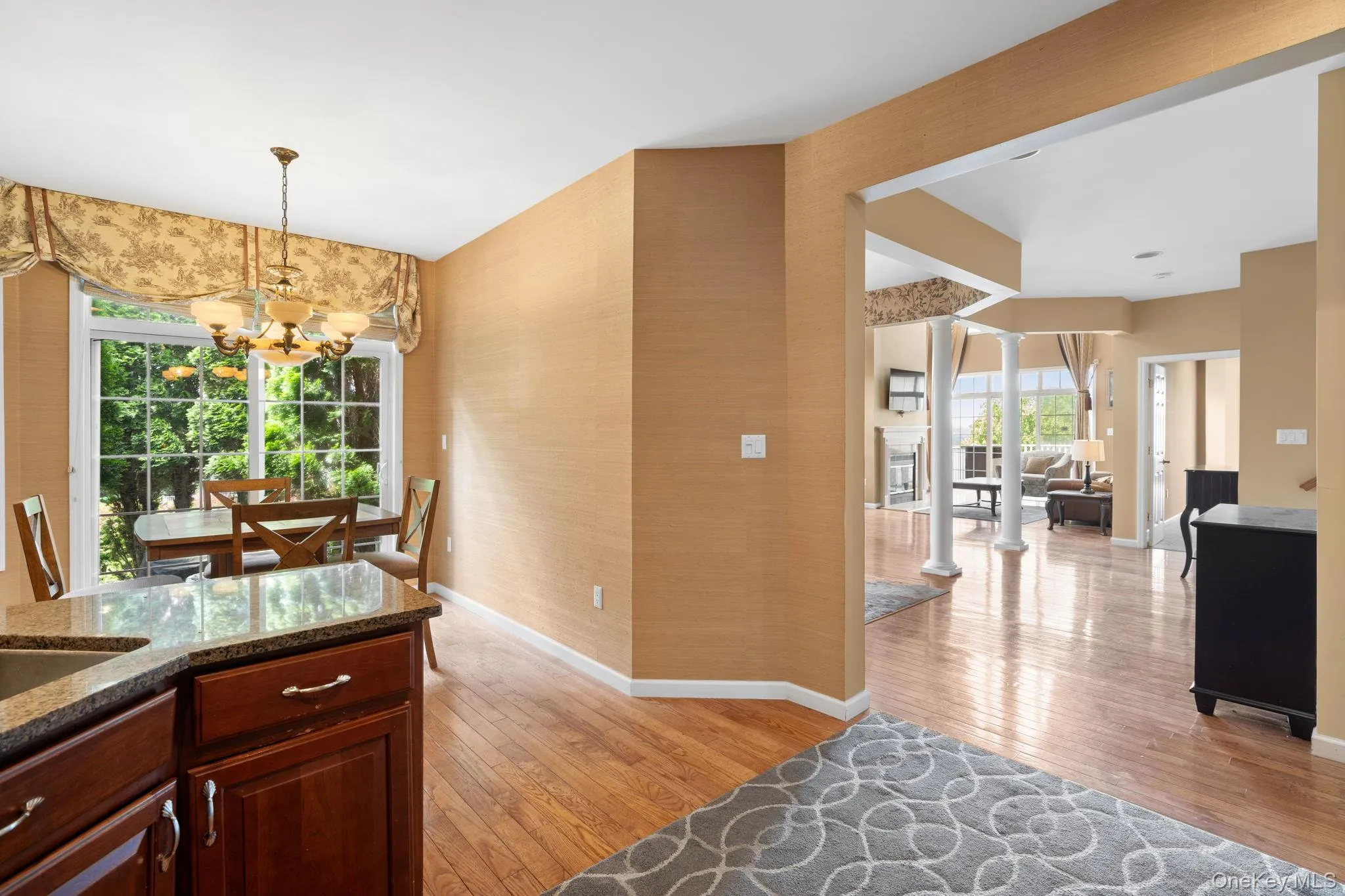 Kitchen with a chandelier, light wood-style floors, stone countertops, and decorative light fixtures Kitchen with a chandelier, light wood-style floors, stone countertops, and decorative light fixtures
