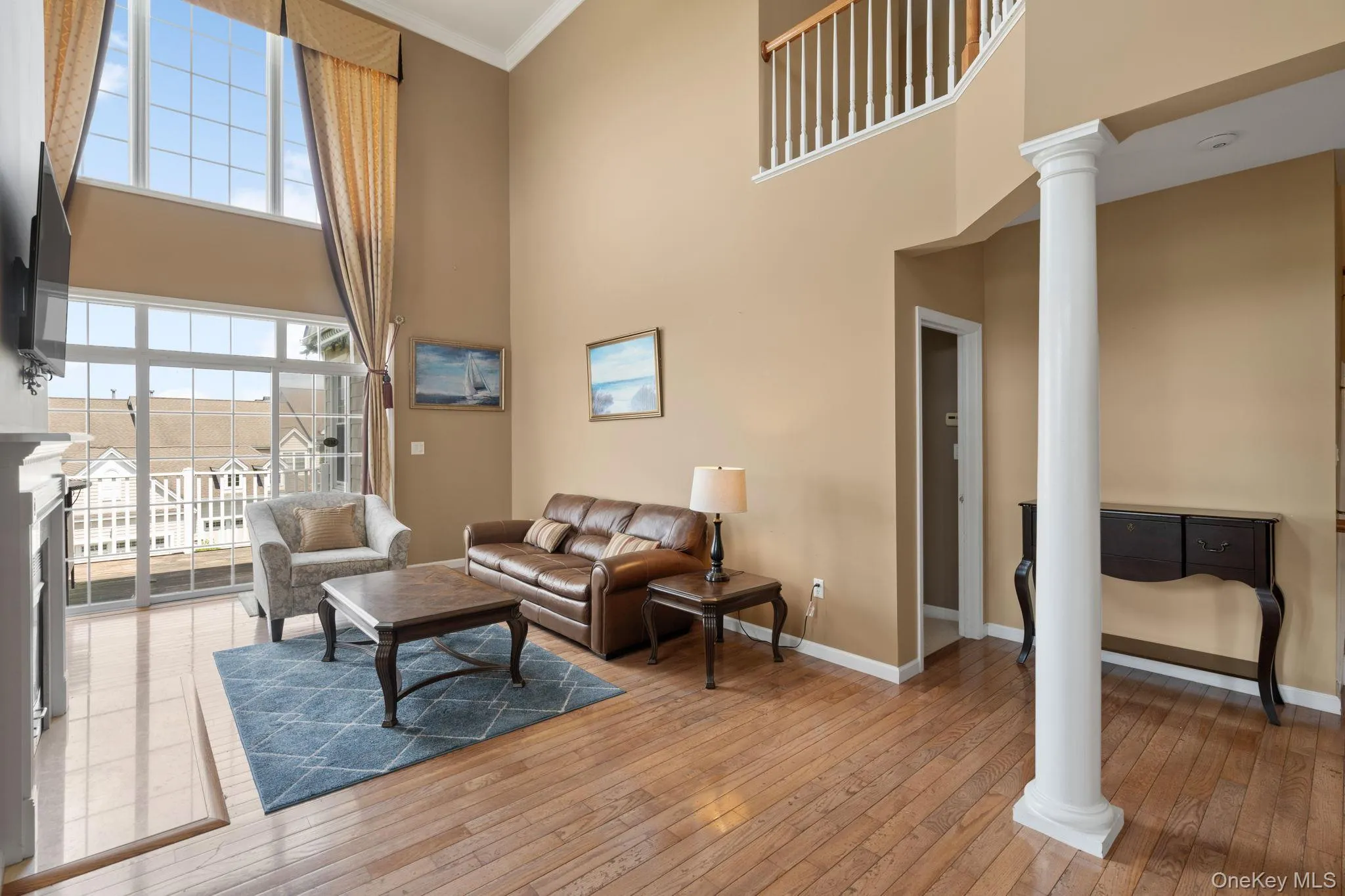 Living area with decorative columns, a towering ceiling, wood-type flooring, and ornamental molding Living area with decorative columns, a towering ceiling, wood-type flooring, and ornamental molding