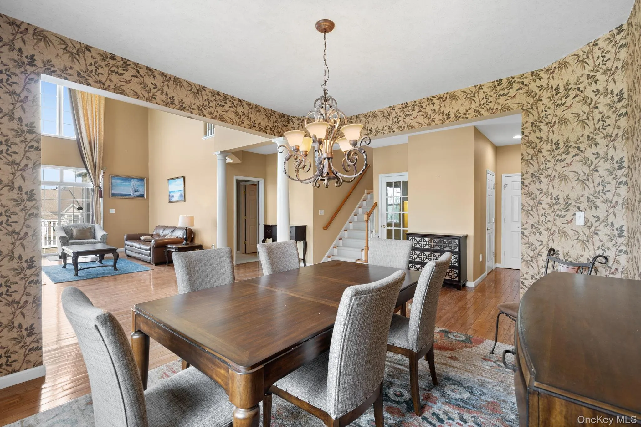 Dining area with wallpapered walls, a chandelier, wood finished floors, and stairway Dining area with wallpapered walls, a chandelier, wood finished floors, and stairway