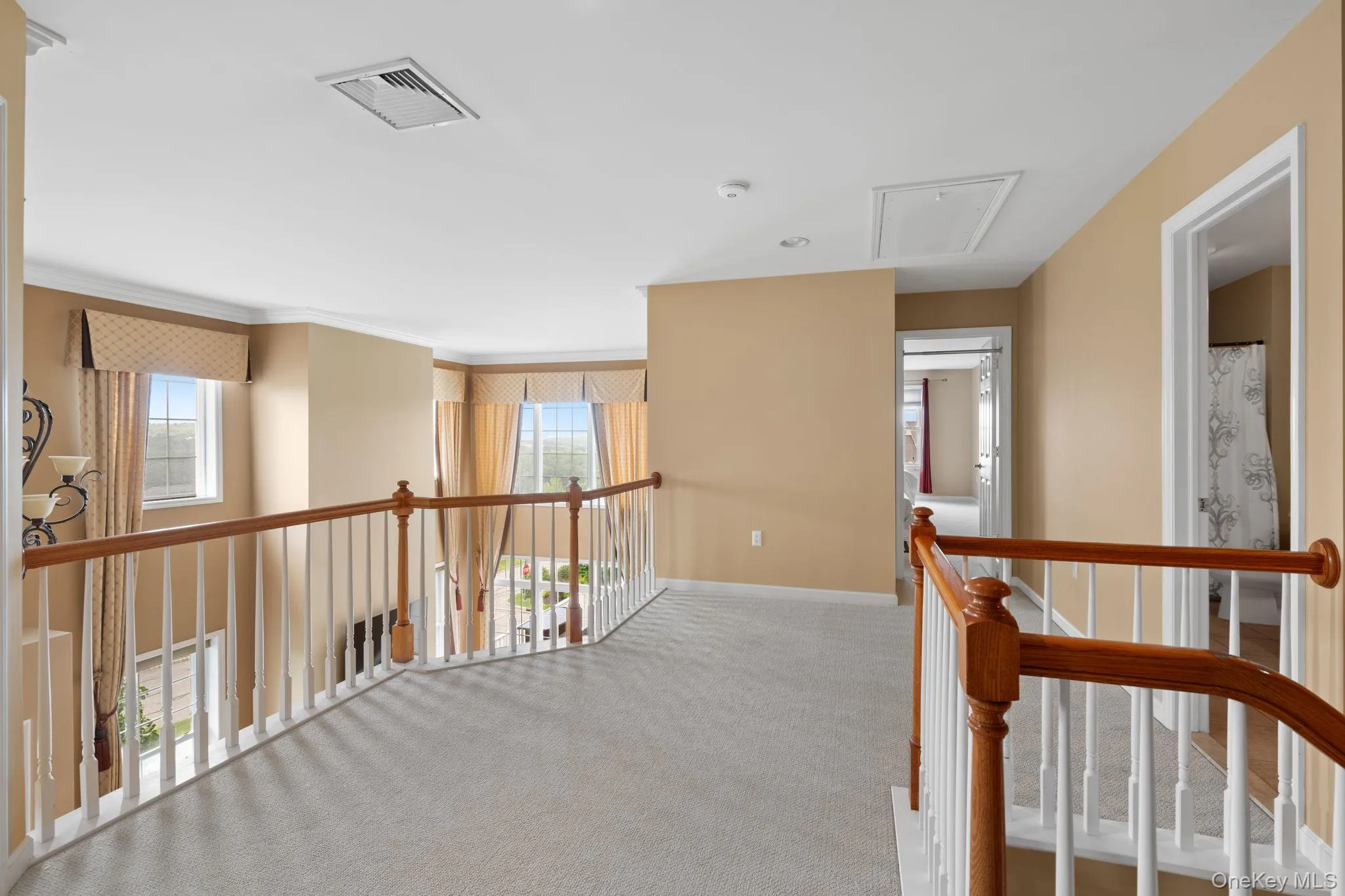 Hall with attic access, carpet floors, an upstairs landing, and crown molding Hall with attic access, carpet floors, an upstairs landing, and crown molding