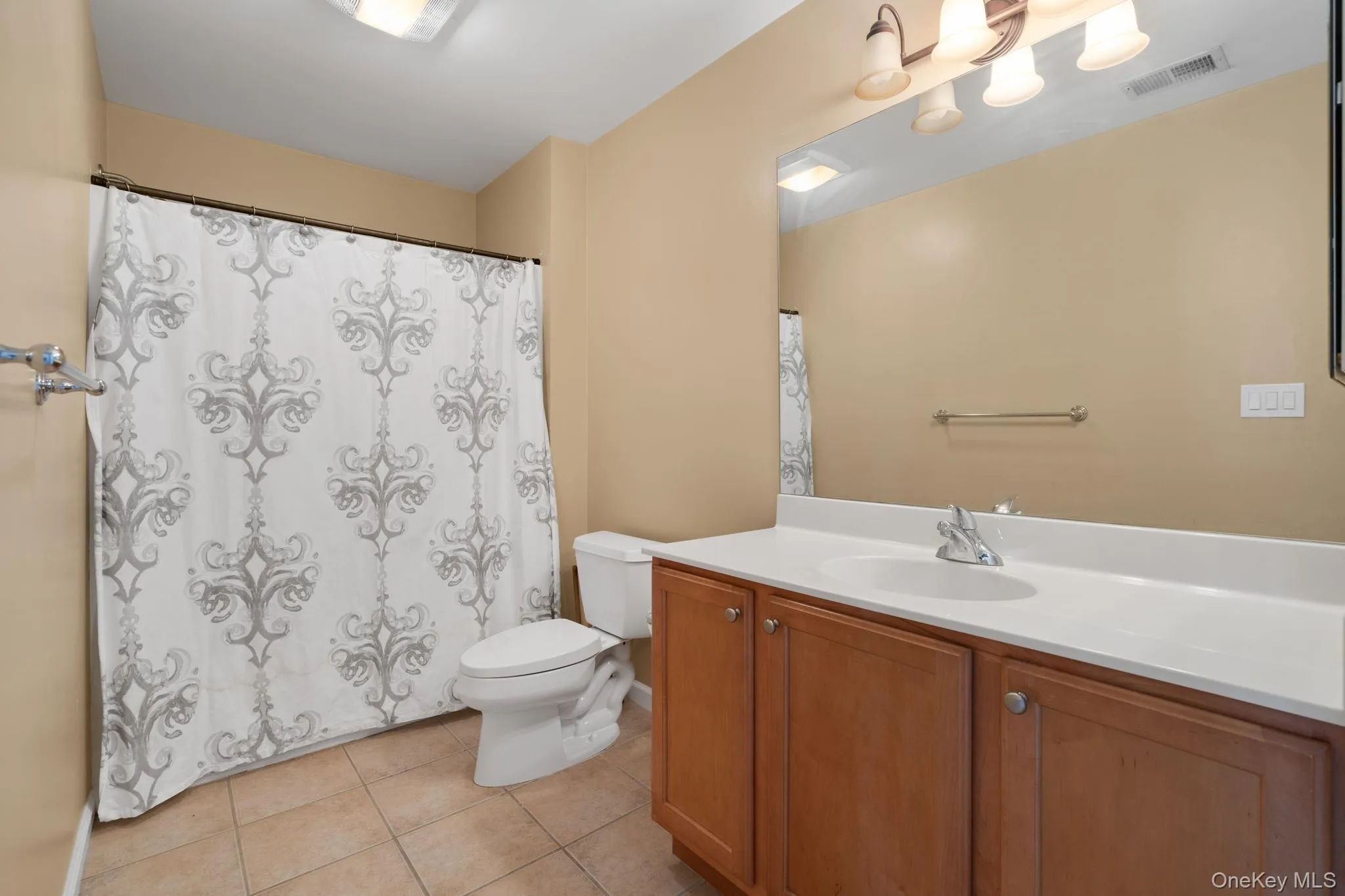 Bathroom featuring vanity, tile patterned flooring, and a shower with curtain Bathroom featuring vanity, tile patterned flooring, and a shower with curtain
