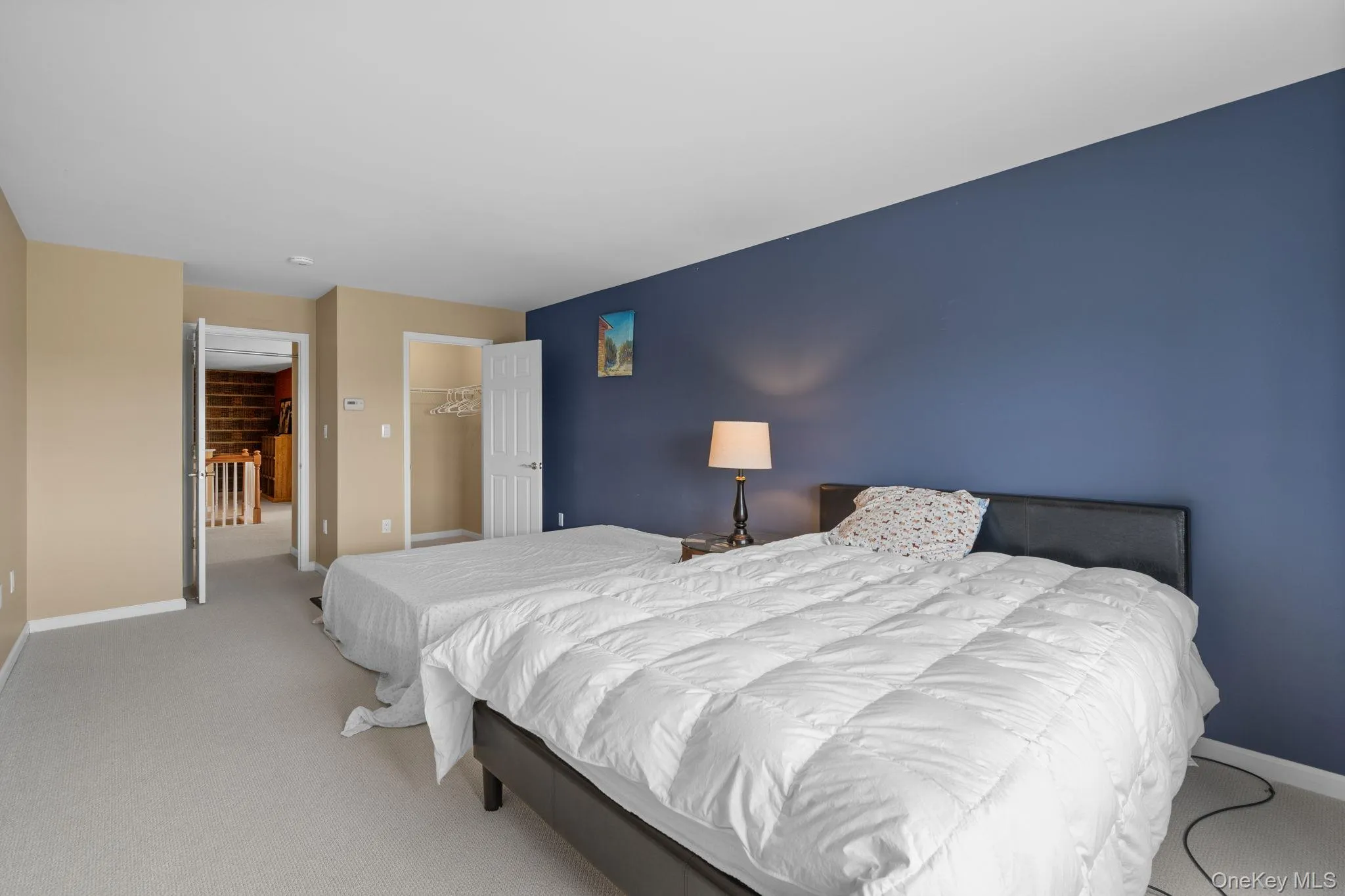 Carpeted bedroom featuring a closet and a spacious closet Carpeted bedroom featuring a closet and a spacious closet