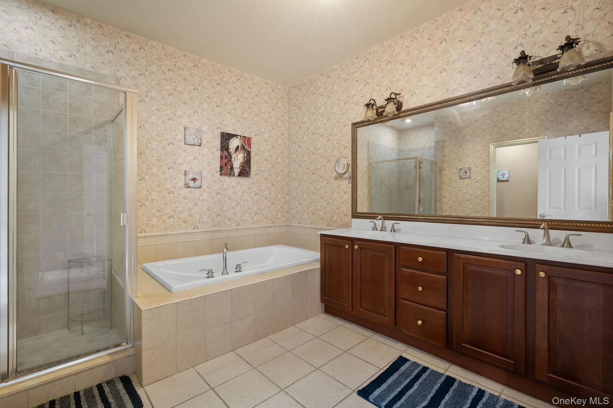 Full bathroom with tile patterned flooring, double vanity, a bath, a shower stall, and wallpapered walls Full bathroom with tile patterned flooring, double vanity, a bath, a shower stall, and wallpapered walls