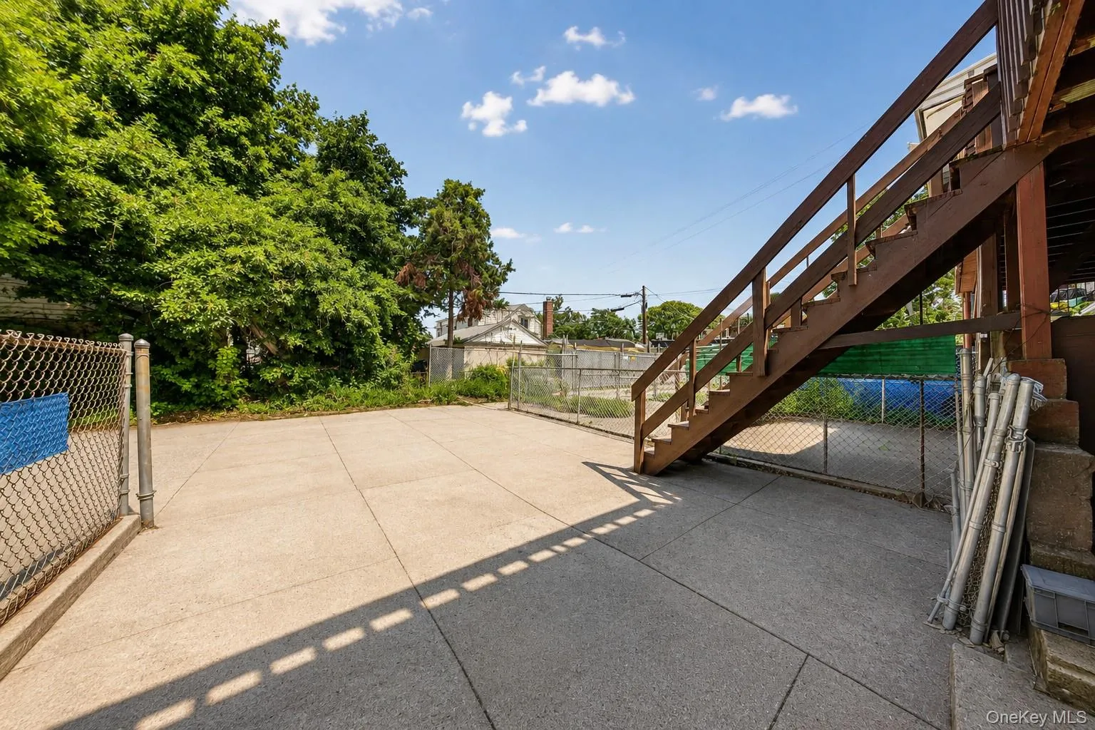 Paved outdoor area featuring chain link fencing and a wood-finish staircase Paved outdoor area featuring chain link fencing and a wood-finish staircase