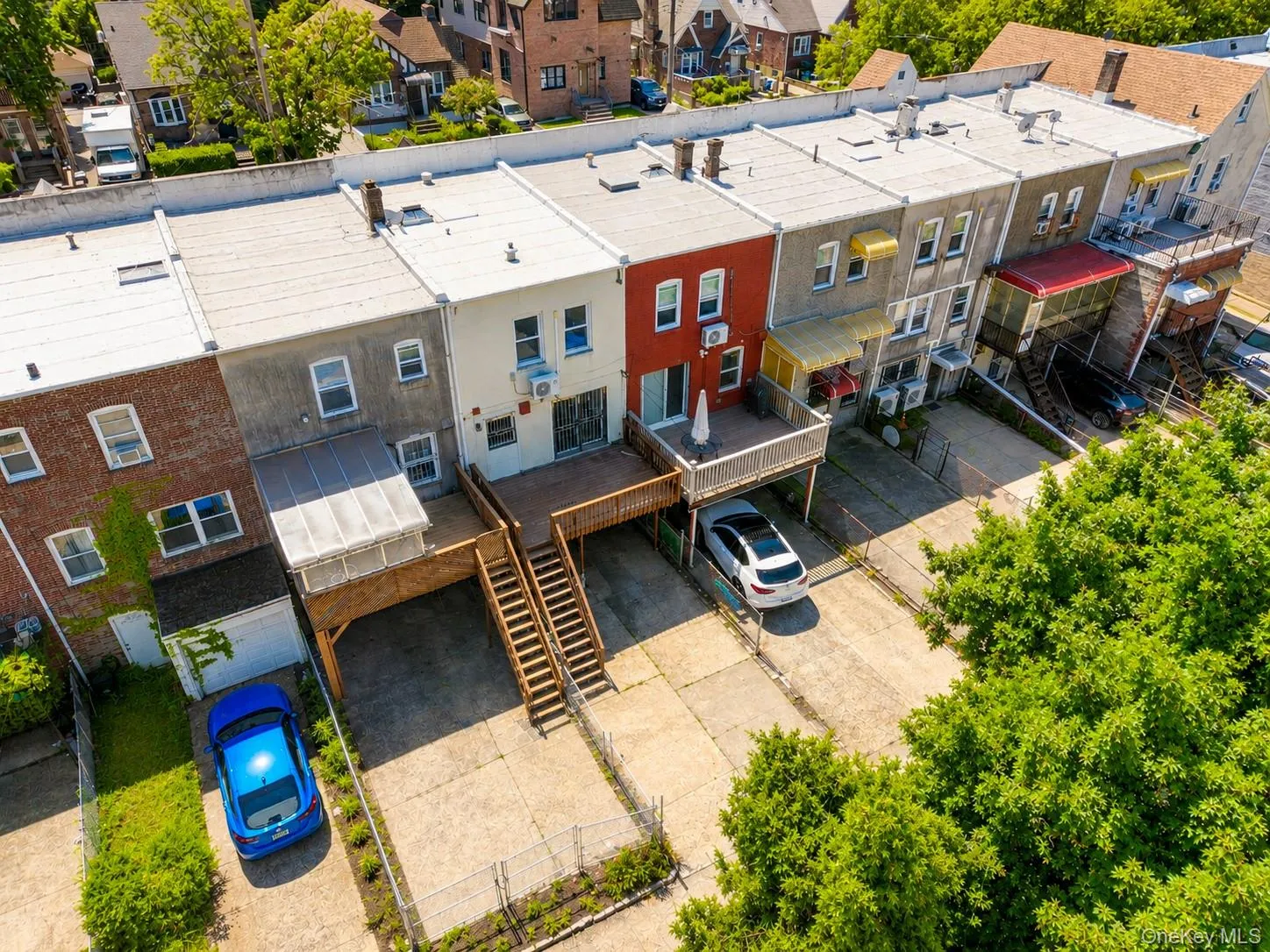 Rear elevated wooden deck, rear concrete driveways, upper-level balcony, and a covered patio area Rear elevated wooden deck, rear concrete driveways, upper-level balcony, and a covered patio area
