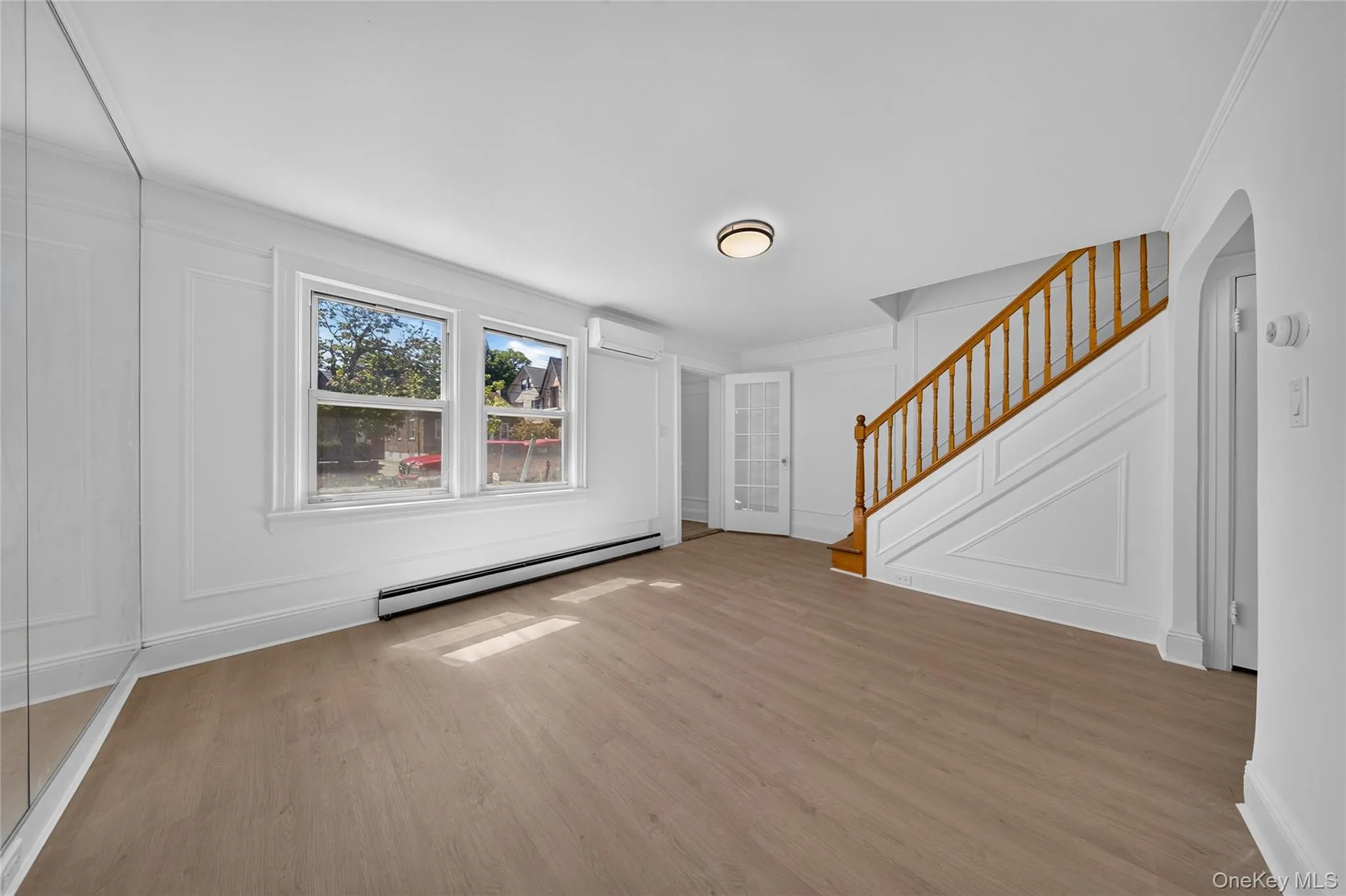 Wood-finish flooring throughout, bright double windows, built-in air conditioning unit, detailed wall molding, and a wood staircase with balusters Wood-finish flooring throughout, bright double windows, built-in air conditioning unit, detailed wall molding, and a wood staircase with balusters