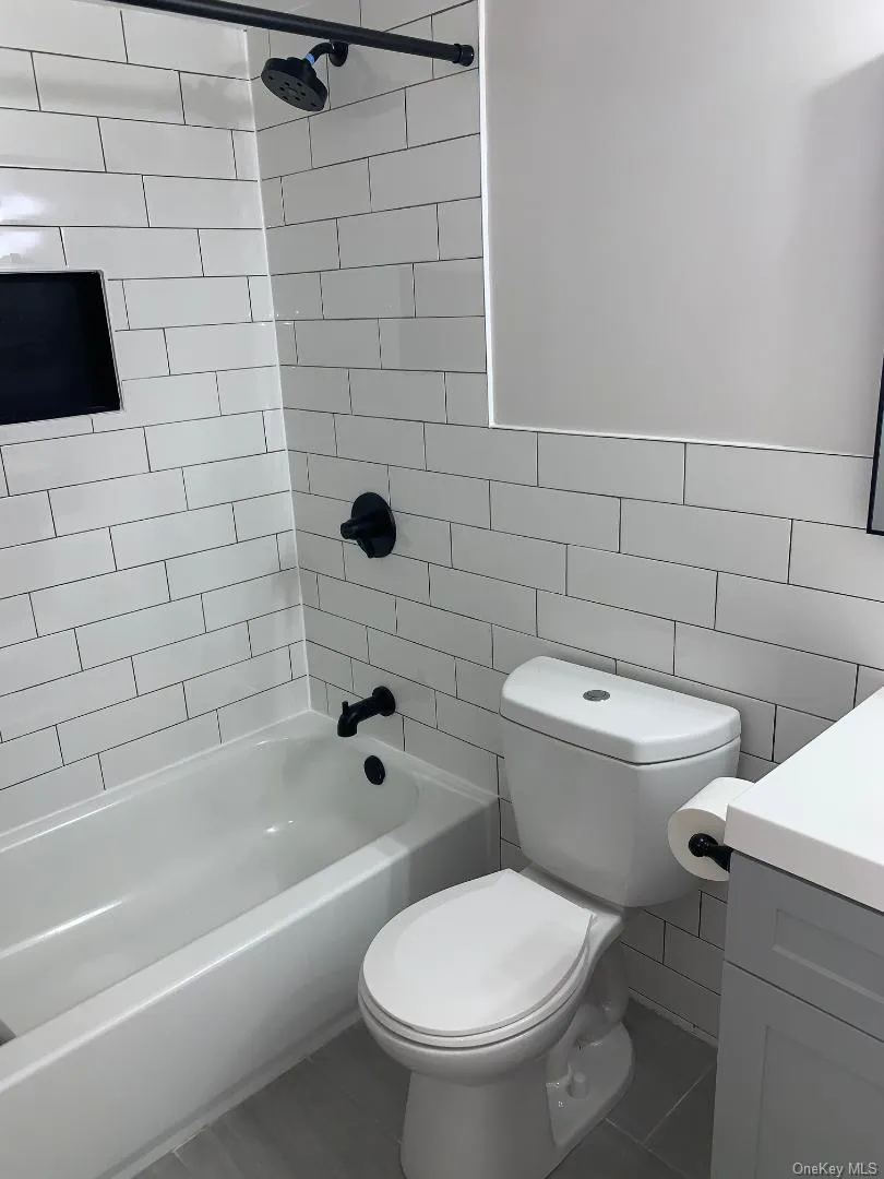 Pretty renovated bathroom with appealing vanity, porcelain tile floors, ceramic tile shower/tub combination, designer faucets Pretty renovated bathroom with appealing vanity, porcelain tile floors, ceramic tile shower/tub combination, designer faucets