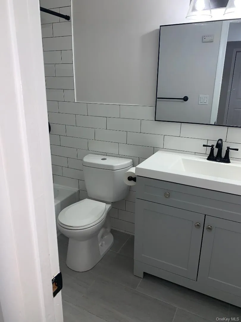 Pretty renovated bathroom with vanity, tile walls, and shower / tub combination Pretty renovated bathroom with vanity, tile walls, and shower / tub combination