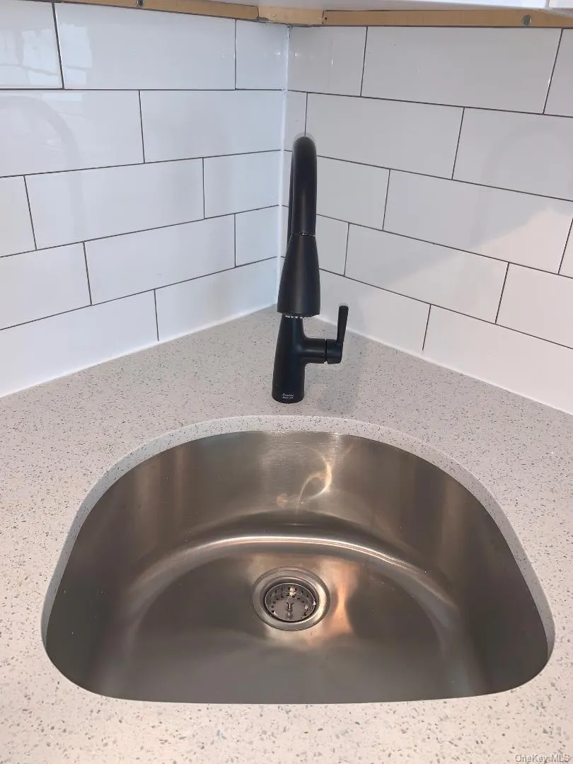 Stylish stainless steel sink, quartz counters, subway tile backsplash and decorator faucet Stylish stainless steel sink, quartz counters, subway tile backsplash and decorator faucet