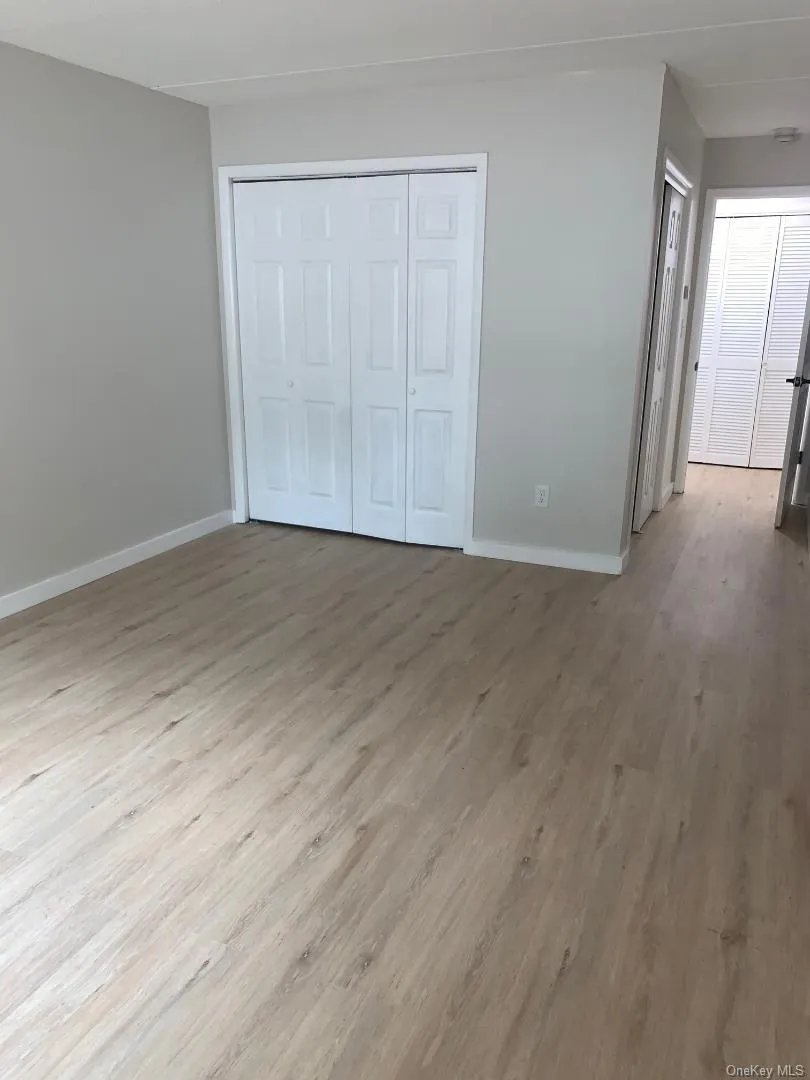 Spacious primary bedroom has wood like floors and 2 double closets Spacious primary bedroom has wood like floors and 2 double closets