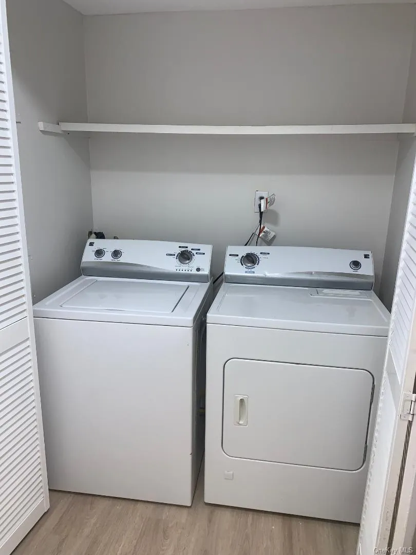 Laundry area featuring light wood-style flooring and washer and dryer Laundry area featuring light wood-style flooring and washer and dryer