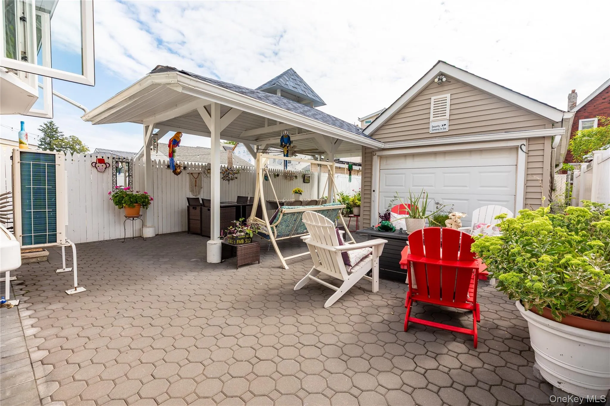 Paver patio featuring a white pergola, detached garage with a white overhead door, and a white privacy fence Paver patio featuring a white pergola, detached garage with a white overhead door, and a white privacy fence