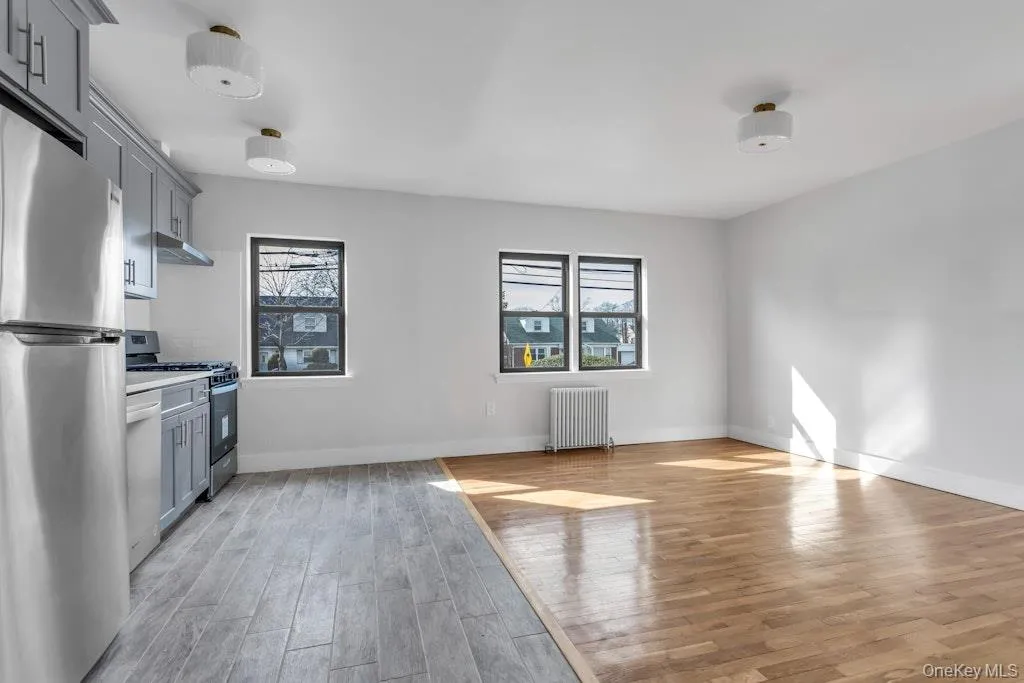 Kitchen featuring radiator, appliances with stainless steel finishes, gray cabinets, and a wealth of natural light Kitchen featuring radiator, appliances with stainless steel finishes, gray cabinets, and a wealth of natural light