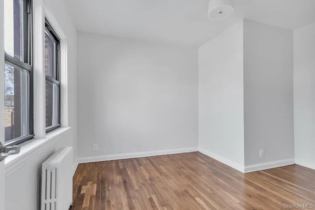 Spare room with radiator, baseboards, and hardwood / wood-style floors Spare room with radiator, baseboards, and hardwood / wood-style floors