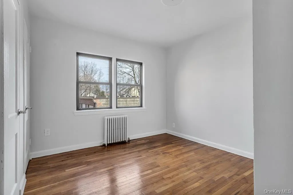 Spare room with radiator, baseboards, and hardwood / wood-style flooring Spare room with radiator, baseboards, and hardwood / wood-style flooring