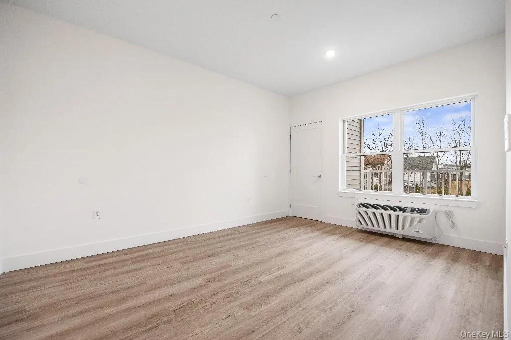 Spare room featuring light hardwood / wood-style floors and an AC wall unit Spare room featuring light hardwood / wood-style floors and an AC wall unit