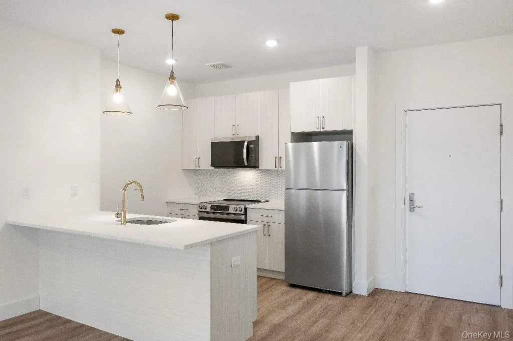 Kitchen featuring pendant lighting, backsplash, white cabinets, sink, and stainless steel appliances Kitchen featuring pendant lighting, backsplash, white cabinets, sink, and stainless steel appliances