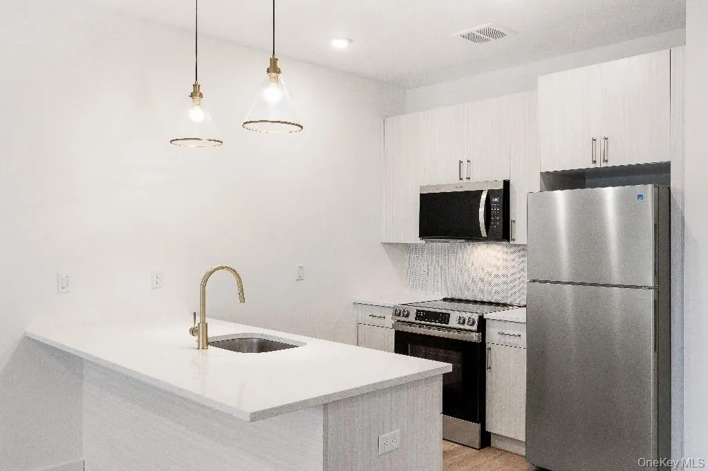 Kitchen with sink, stainless steel appliances, kitchen peninsula, pendant lighting, and decorative backsplash Kitchen with sink, stainless steel appliances, kitchen peninsula, pendant lighting, and decorative backsplash