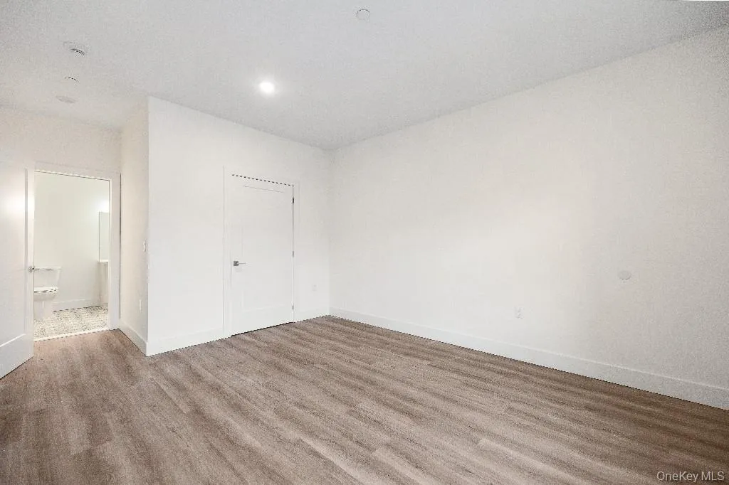 Unfurnished bedroom featuring connected bathroom and hardwood / wood-style floors Unfurnished bedroom featuring connected bathroom and hardwood / wood-style floors