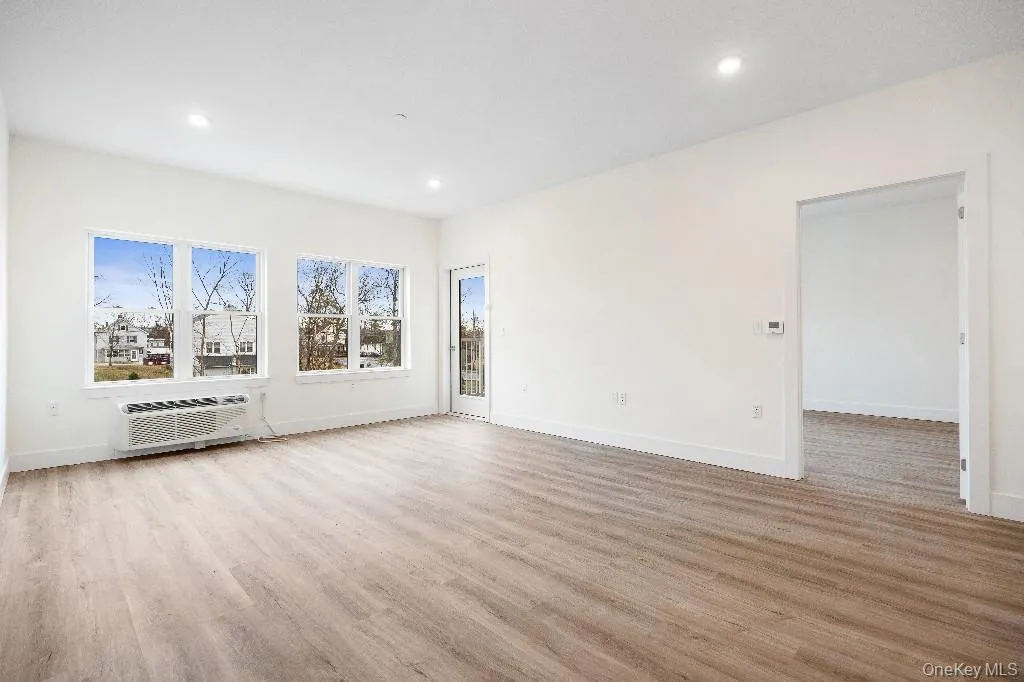 Spare room featuring light hardwood / wood-style flooring and a wall mounted air conditioner Spare room featuring light hardwood / wood-style flooring and a wall mounted air conditioner