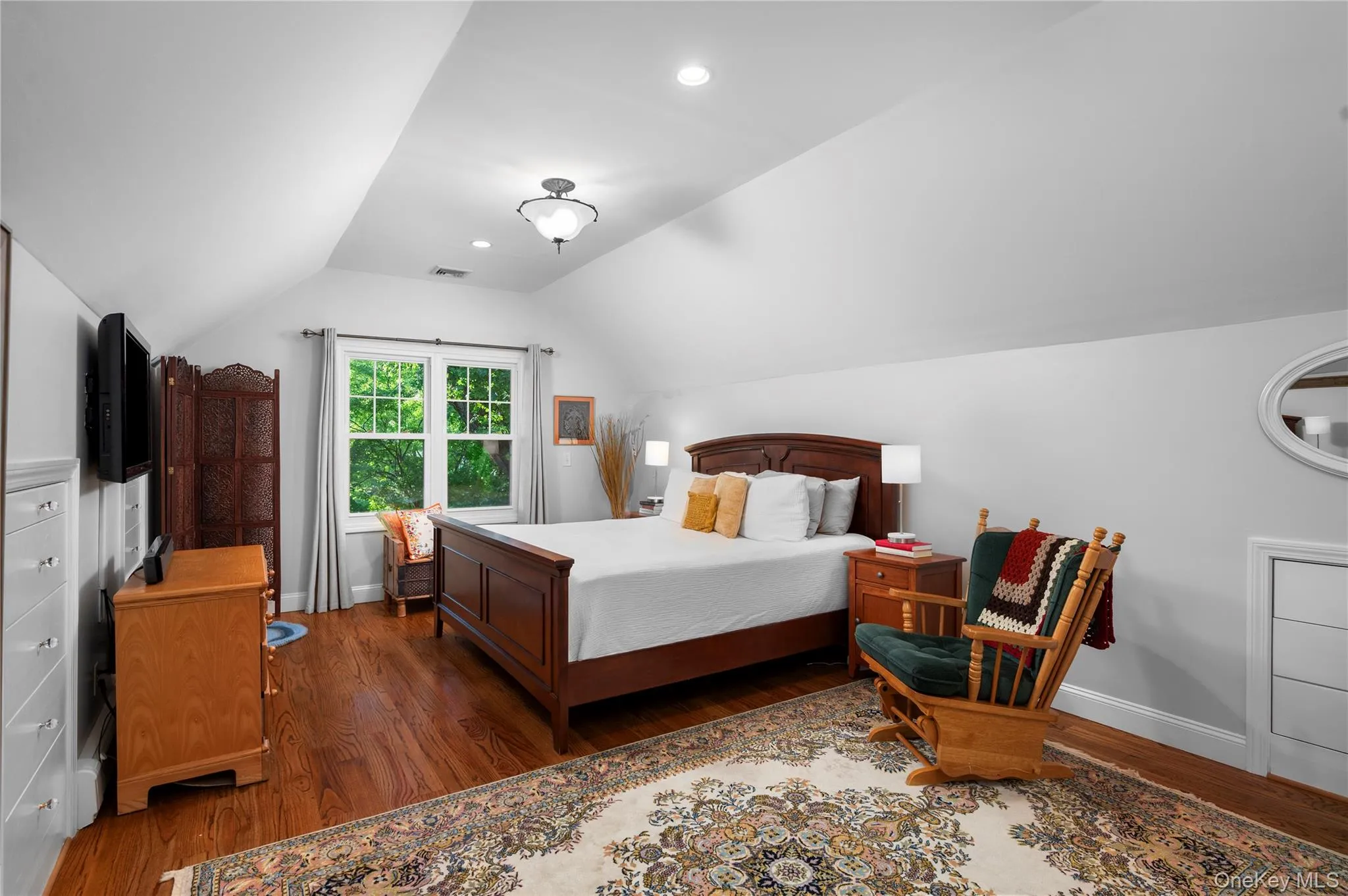 The primary bedroom features built-in drawers, hardwood floors, and cathedral ceilings The primary bedroom features built-in drawers, hardwood floors, and cathedral ceilings