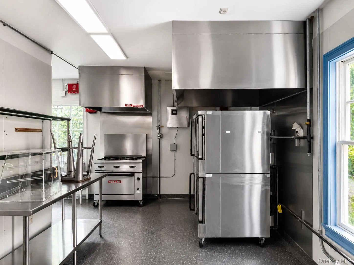 Commercial-grade kitchen featuring stainless steel appliances, extensive stainless steel countertops, and industrial lighting Commercial-grade kitchen featuring stainless steel appliances, extensive stainless steel countertops, and industrial lighting