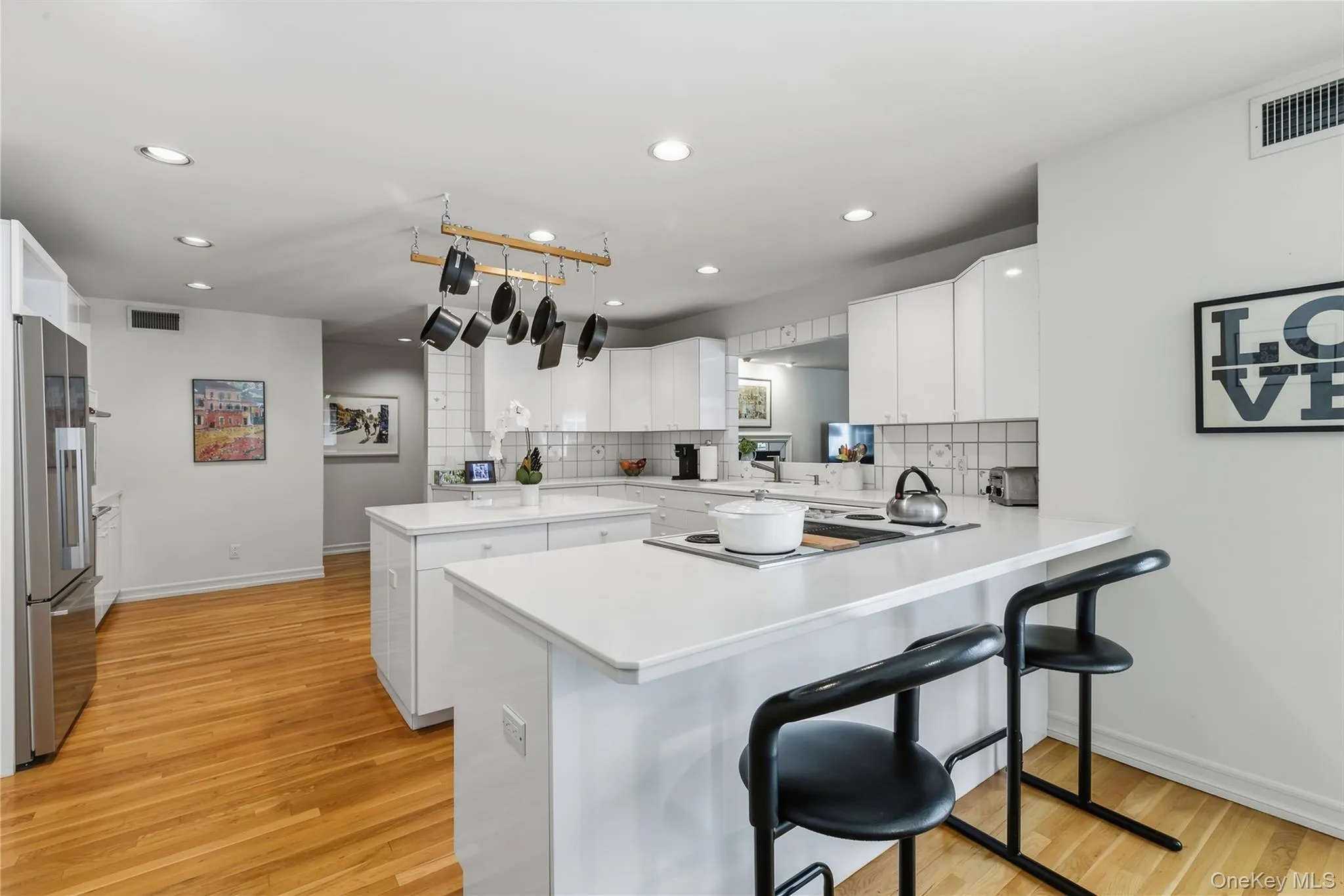 Kitchen features recessed lighting, hardwood floors, electric cook top, Corian countertops and breakfast bar, Fisher & Paykel stainless steel refrigerator. Kitchen features recessed lighting, hardwood floors, electric cook top, Corian countertops and breakfast bar, Fisher & Paykel stainless steel refrigerator.