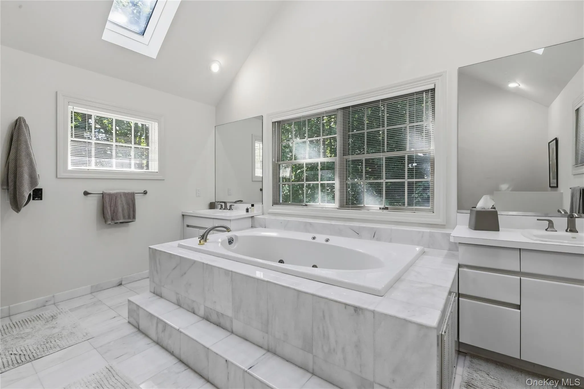 Light and bright primary bathroom features skylights, white marble flooring, his and her vanities, Jacuzzi whirlpool , separate stall shower and oversized windows. Light and bright primary bathroom features skylights, white marble flooring, his and her vanities, Jacuzzi whirlpool , separate stall shower and oversized windows.