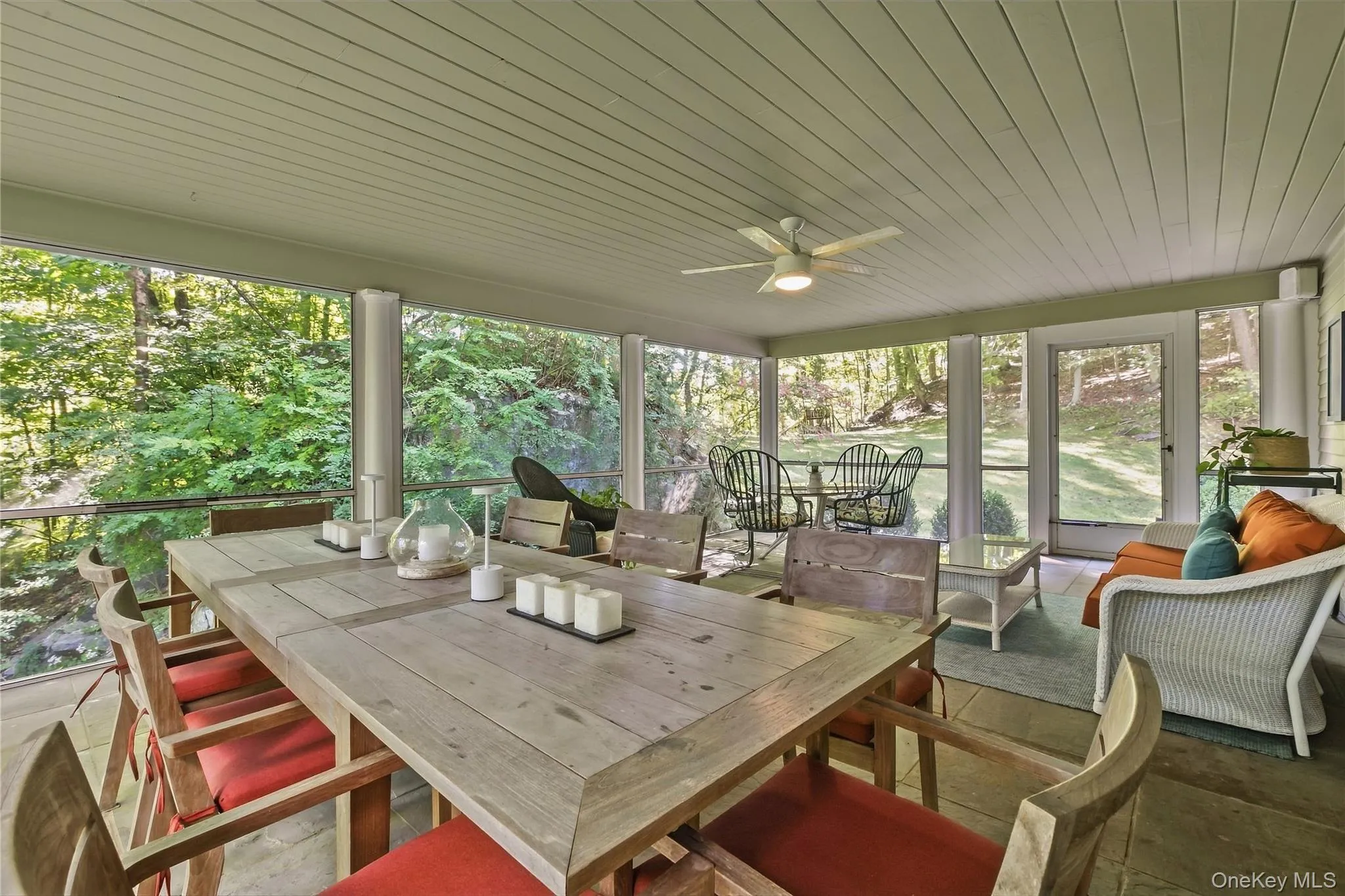 Serene screened-in porch featuring a wood-paneled ceiling, bluestone flooring, ceiling fan, door out to back deck Serene screened-in porch featuring a wood-paneled ceiling, bluestone flooring, ceiling fan, door out to back deck