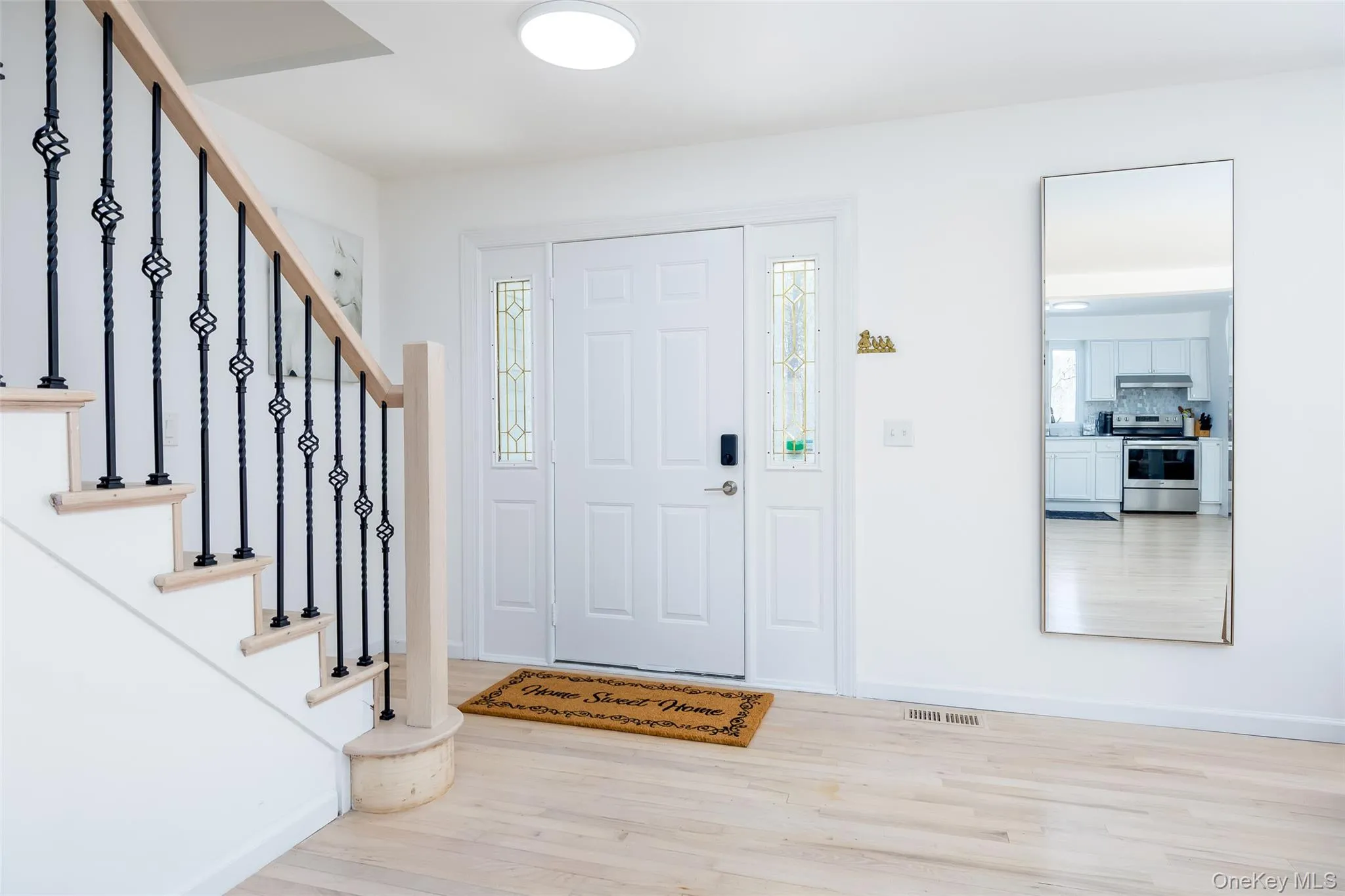 Foyer entrance featuring wood finished floors, stairway, plenty of natural light, and baseboards Foyer entrance featuring wood finished floors, stairway, plenty of natural light, and baseboards