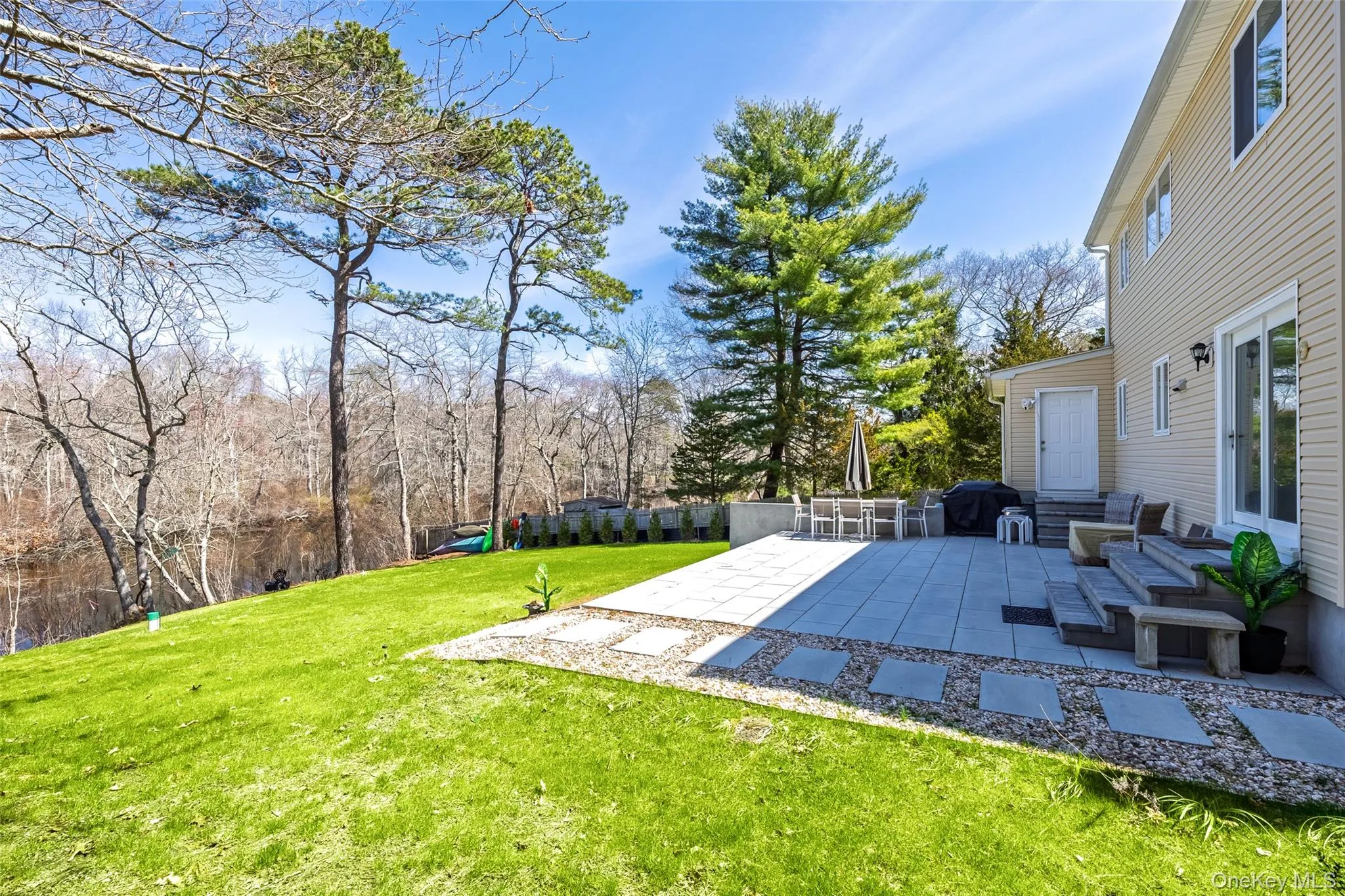 View of green lawn featuring a patio area and view of wooded area View of green lawn featuring a patio area and view of wooded area