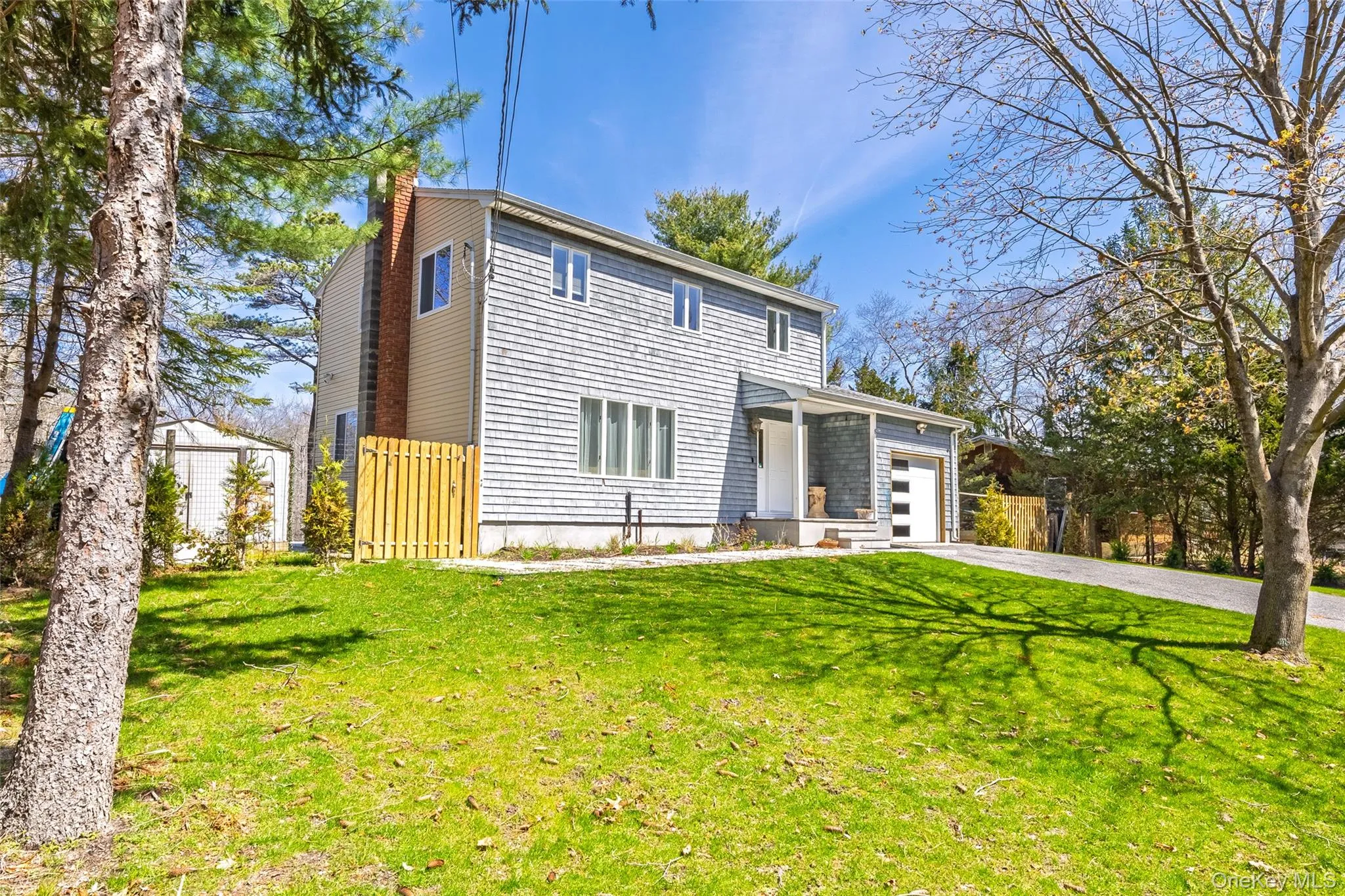 View of front of home with an attached garage, driveway, and a chimney View of front of home with an attached garage, driveway, and a chimney